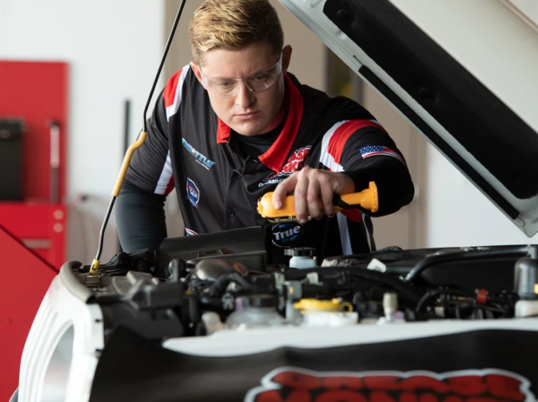 Technician checking brake pads on a car.
