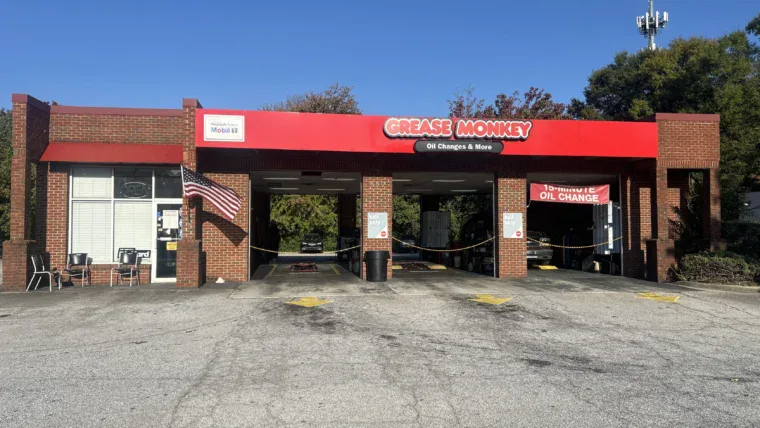 Exterior of Grease Monkey oil change center before renovation, showing older signage and faded building colors.