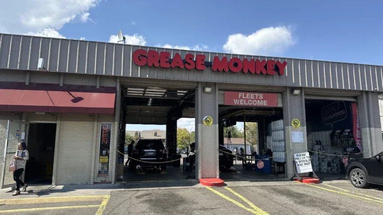 Exterior of Grease Monkey oil change center before renovation, showing older signage and faded building colors.