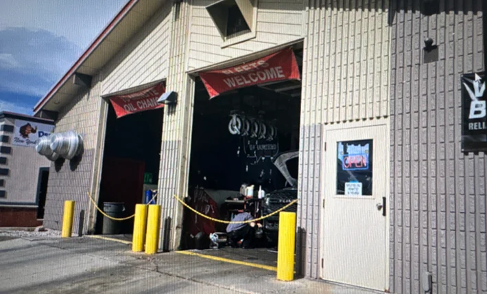 Exterior of Grease Monkey oil change center before renovation, showing older signage and faded building colors.