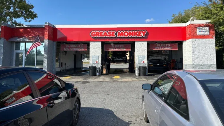 Exterior of Grease Monkey oil change center before renovation, showing older signage and faded building colors.