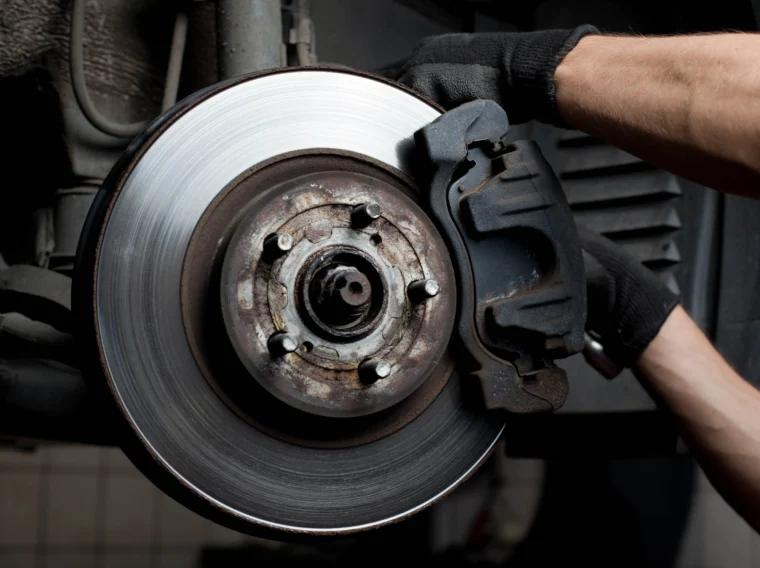 Closeup of car mechanic repairing brake pads and rotors.
