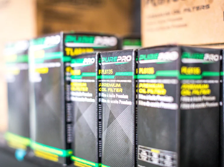Several PurePro premium oil filter boxes are lined up on a store shelf, highlighting their product labels—ideal for those seeking quality filter services.