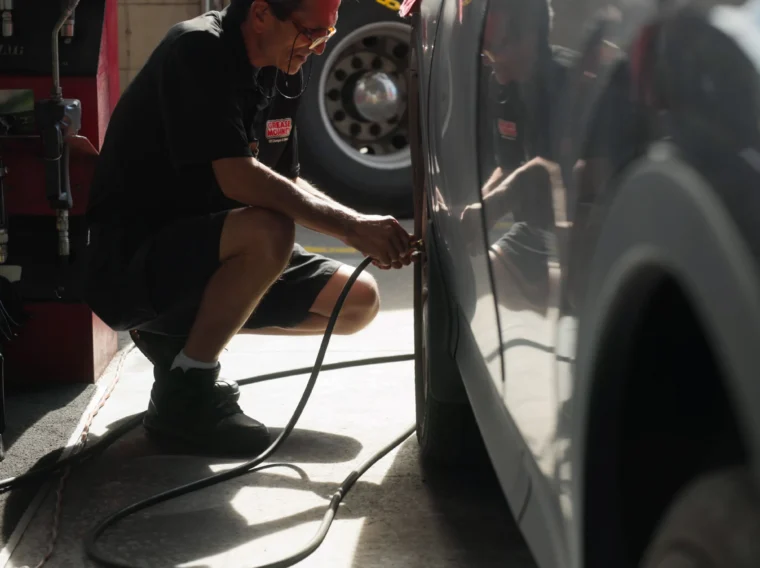 A Grease Monkey technician filling a tire with air.