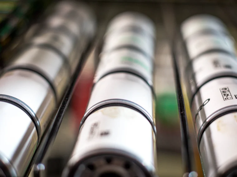 Close-up view of cylindrical oil filters arranged in parallel rows on a metal rack.