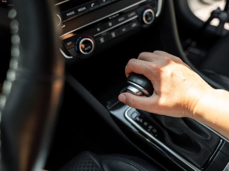 Driver hand rests on gear shift of automatic transmission in car